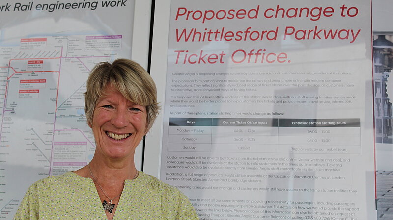 Pippa Heylings, Liberal Democrats parliamentary candidate for South Cambridgeshire, stands in front of an announcement about changes to the Whittlesford Parkway ticket office
