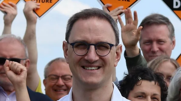 Ian Sollom standing in front of his campaigners who are holding Lib Dem banners