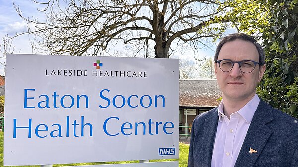 Ian Sollom standing next to the Eaton Socon GP surgery sign