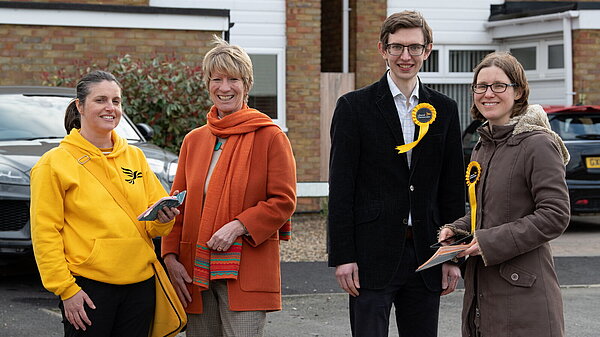 Pippa Heylings, Lib Dem Parliamentary candidate for South Cambs. stands with three volunteers in front of some houses. Pippa stands second from left.