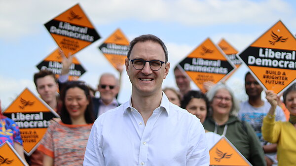 Ian Sollom, Lib Dem Parliamentary Candidate for St Neots and Mid Camb, standing in front of campaigners. Ian is in the foreground while the campaigners are behind him, slightly out of focus so that Ian is highlighted.